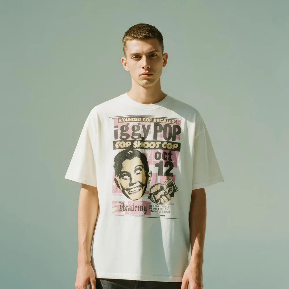Unisex oversized off-white t-shirt made from 100% premium cotton. This tee features a vintage-style graphic designed to look like a punk rock concert poster for an 'Iggy Pop' event. The design includes bold typography, a stylized portrait, and event details, creating an authentic retro look perfect for fans of music history and punk-inspired fashion